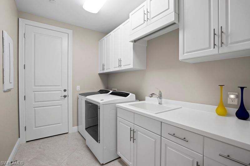 Laundry room featuring cabinet space, washer and clothes dryer, electric panel, and light tile patterned floors