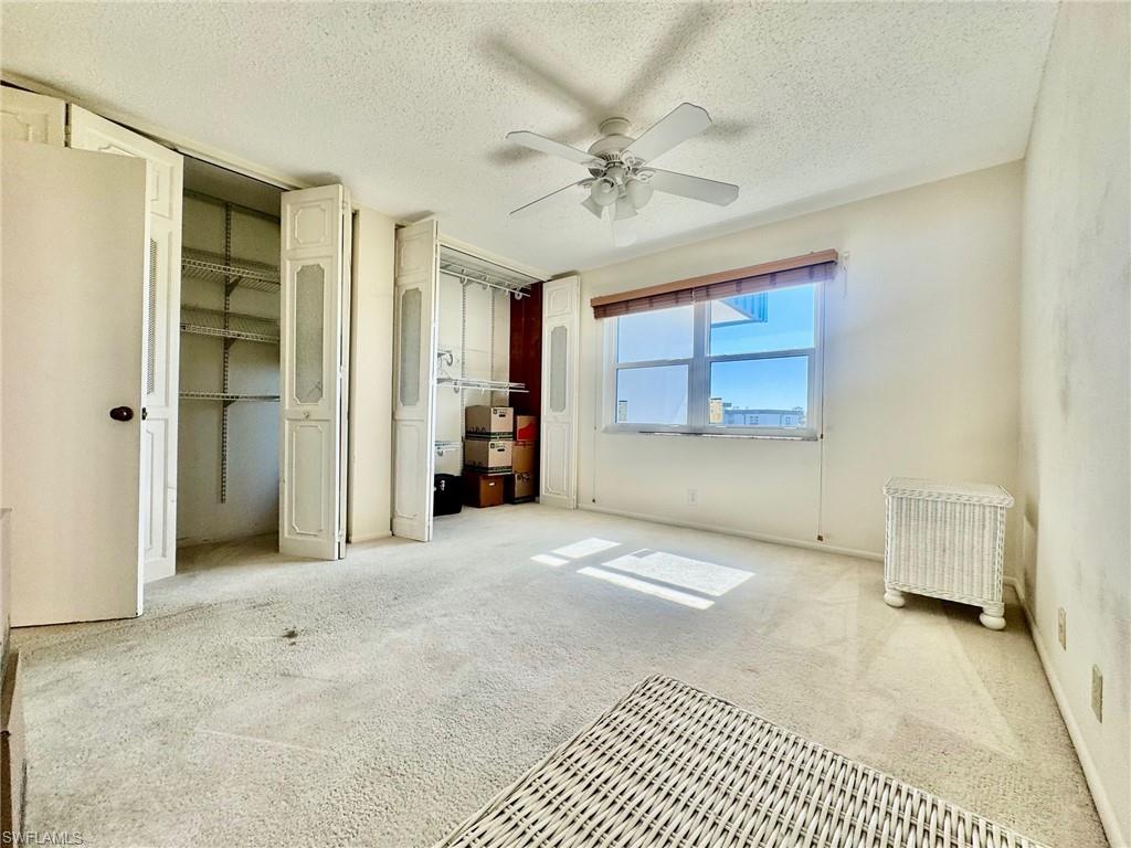 Unfurnished bedroom featuring two closets, carpet floors, ceiling fan, a textured ceiling, and radiator heating unit