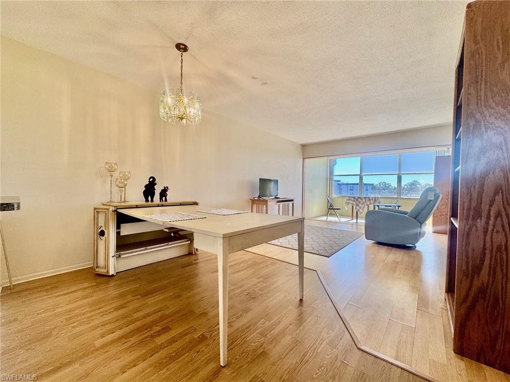 Dining room featuring a textured ceiling, light wood-style floors, a chandelier, and a desk