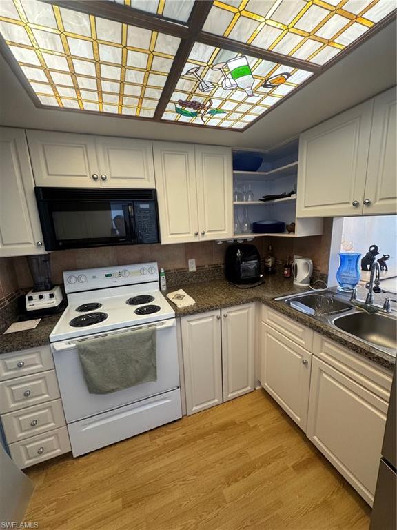 Kitchen with black range, light wood-style flooring, white cabinets, and open shelves