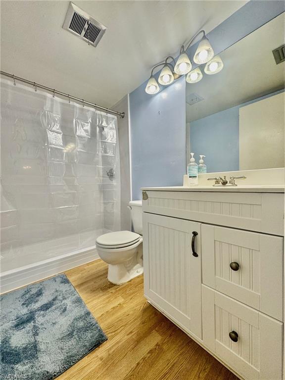 Full bath with vanity, a stall shower, and light wood finished floors
