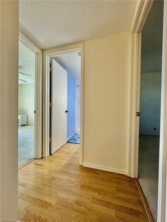 Hall with a textured ceiling and wood finished floors