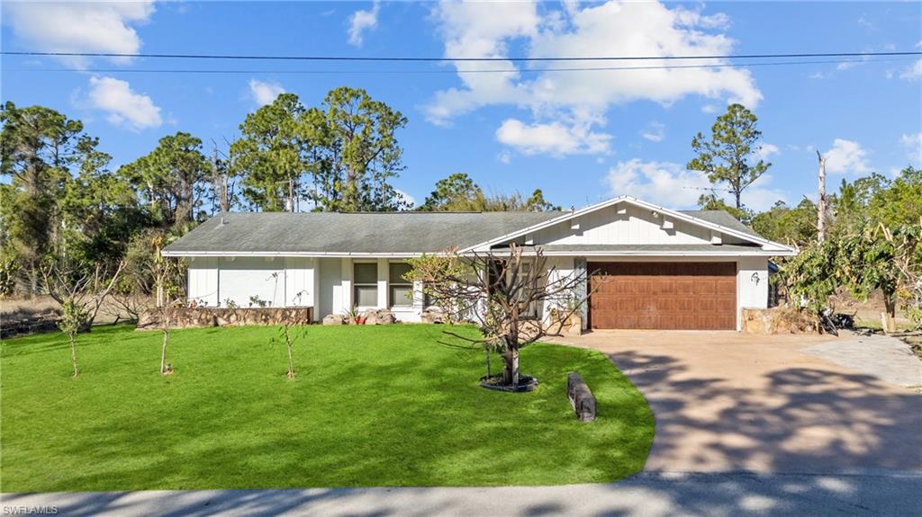 View of front of house featuring a garage, a front yard, and driveway