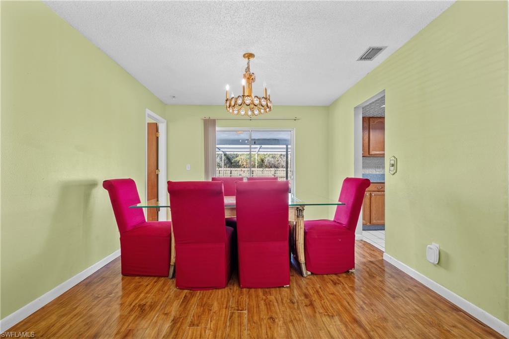 Dining room with hanging lights, light wood finished floors, and a textured ceiling