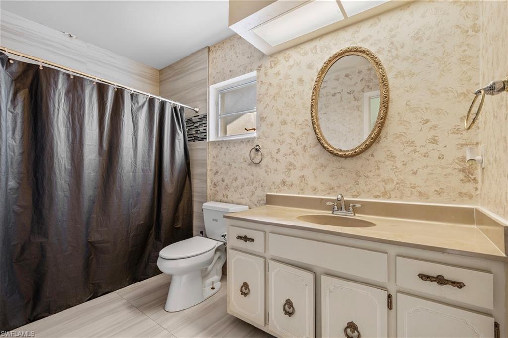 Bathroom with vanity, a shower with curtain, and wallpapered walls