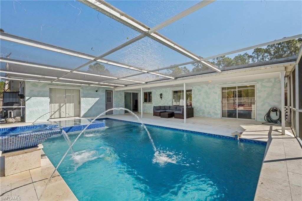Integrated pool / hot tub with a patio, glass enclosure, a sunroom, and outdoor furniture
