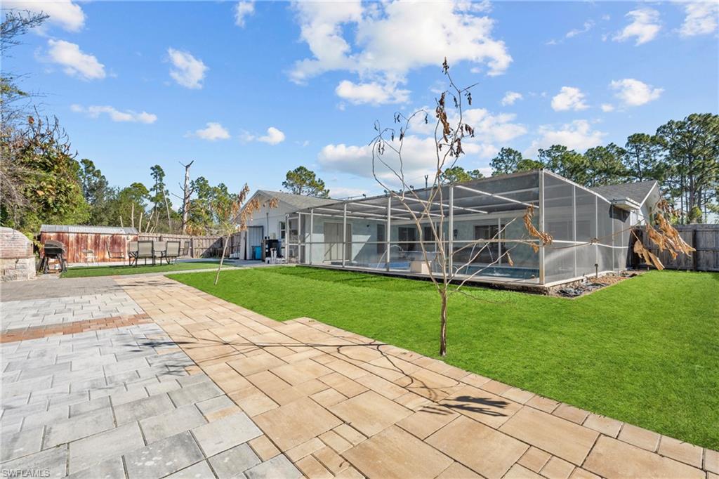 Back of house featuring a fenced backyard, a sunroom, a swimming pool, a patio, and a lanai