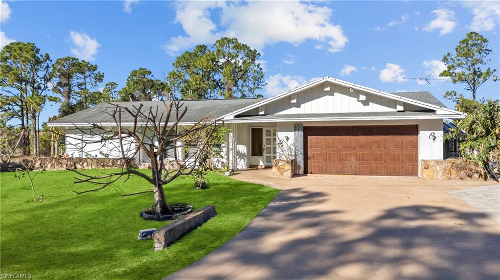 Ranch-style house with an attached garage, a front lawn, and driveway