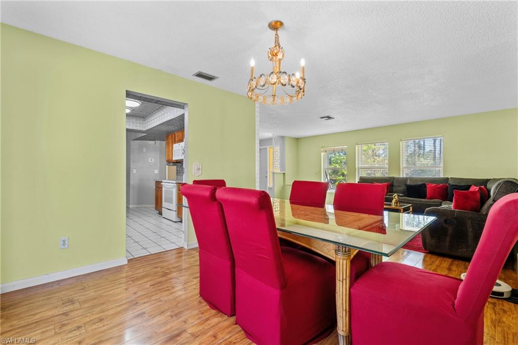 Dining space featuring light wood-type flooring, hanging lights, and a textured ceiling