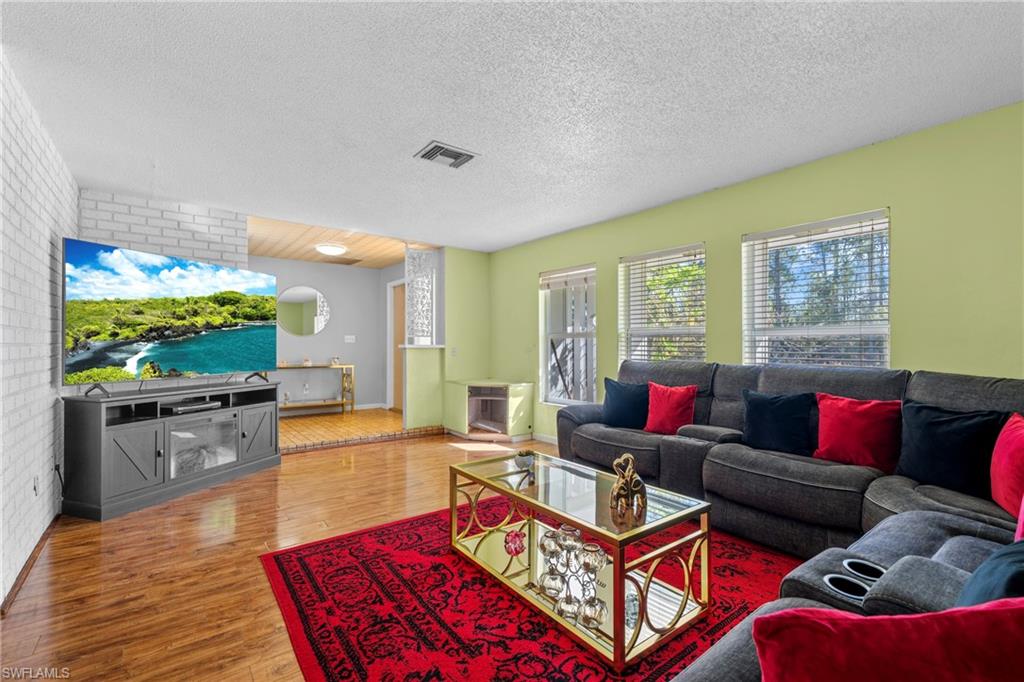 Living room with wood finished floors, a textured ceiling, and brick wall