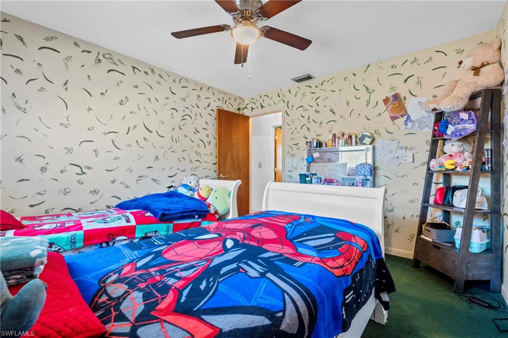 Bedroom featuring wallpapered walls, ceiling fan, and dark carpet