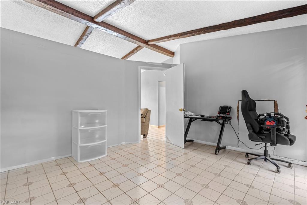 Office space with baseboards and beam ceiling