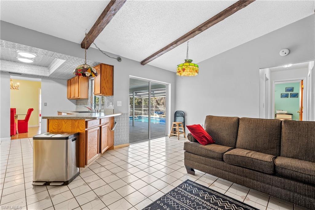 Living area featuring a textured ceiling, beam ceiling, and light tile patterned floors