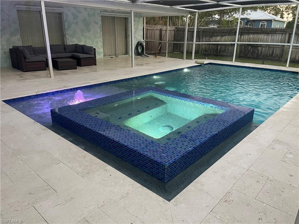 Combined pool / hot tub featuring a patio, a lanai, a fenced backyard, and an outdoor lounge area