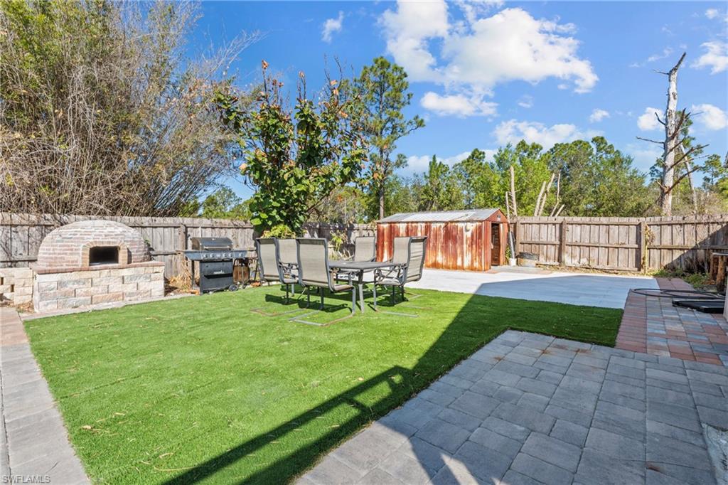 Fenced backyard with a patio, outdoor dining space, and a shed