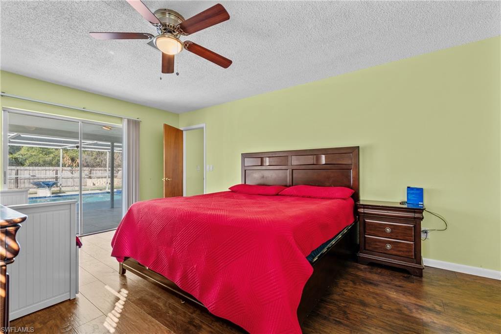 Bedroom with dark wood-style flooring, access to outside, a textured ceiling, and ceiling fan
