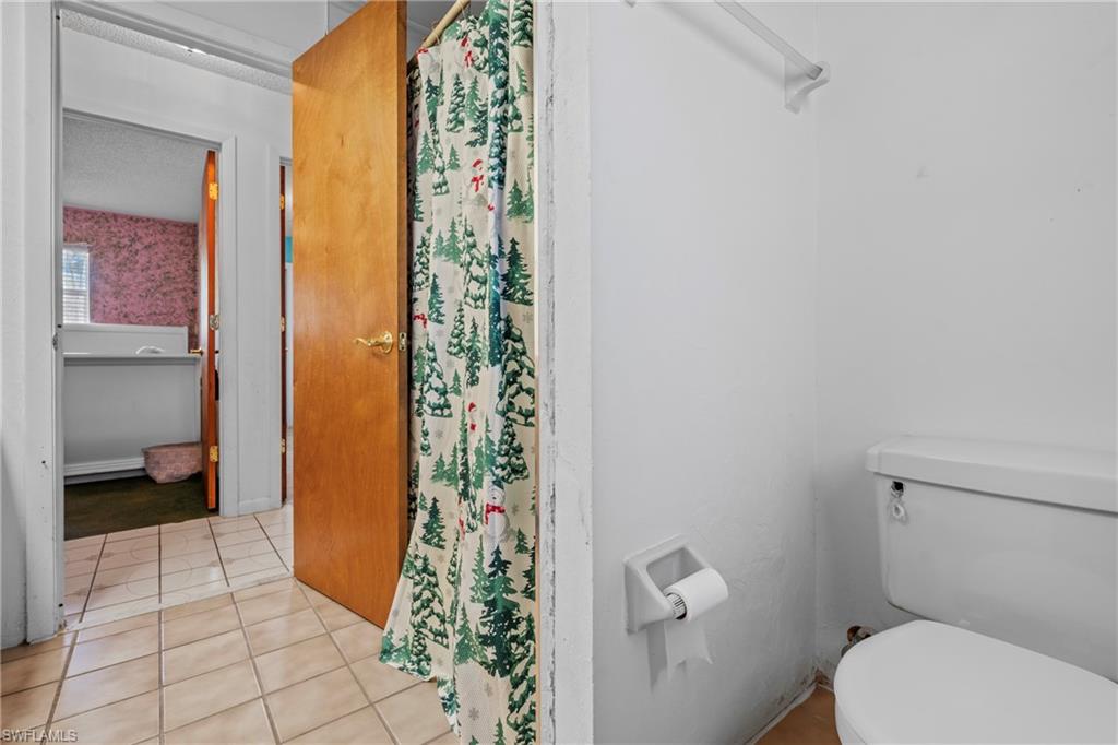 Bathroom with a shower with curtain and light tile patterned flooring