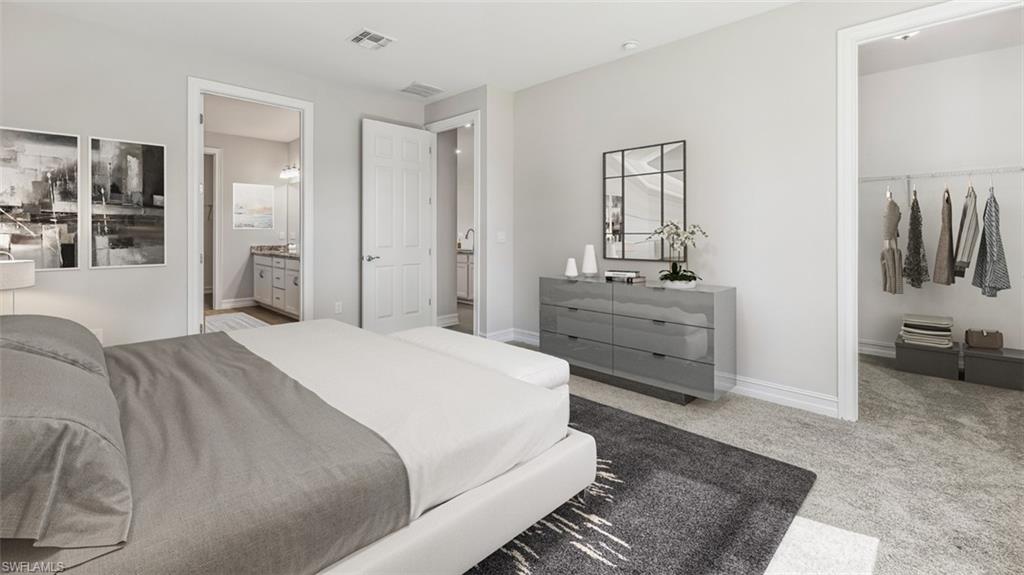 This image is virtually staged. Bedroom featuring light carpet, a walk in closet, and ensuite bathroom
