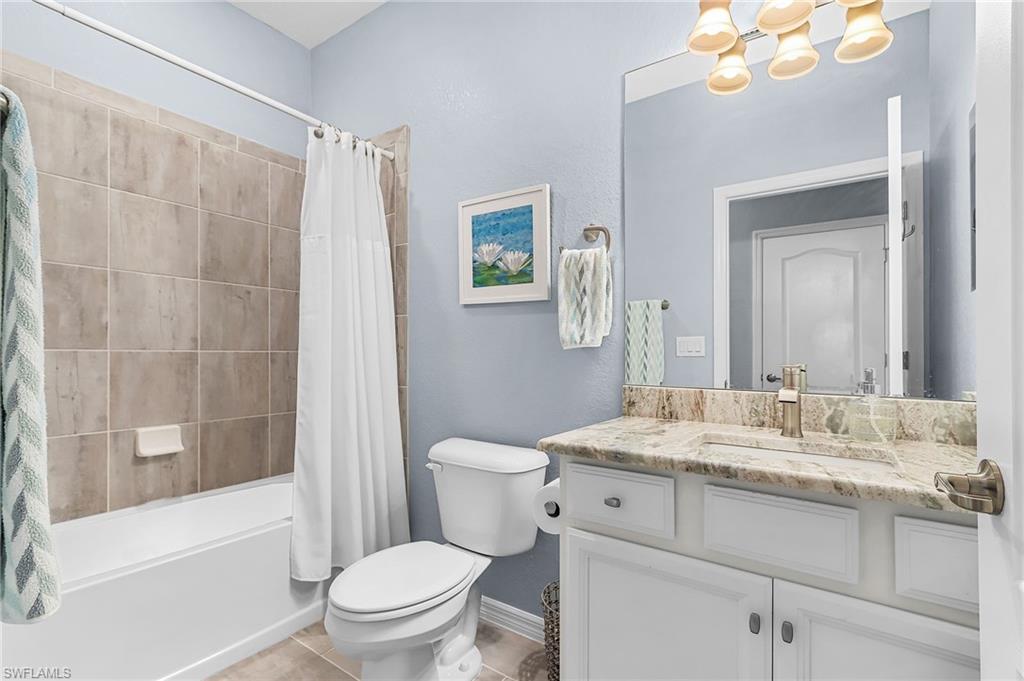 Full bathroom featuring vanity, shower / bathtub combination with curtain, and light tile patterned floors