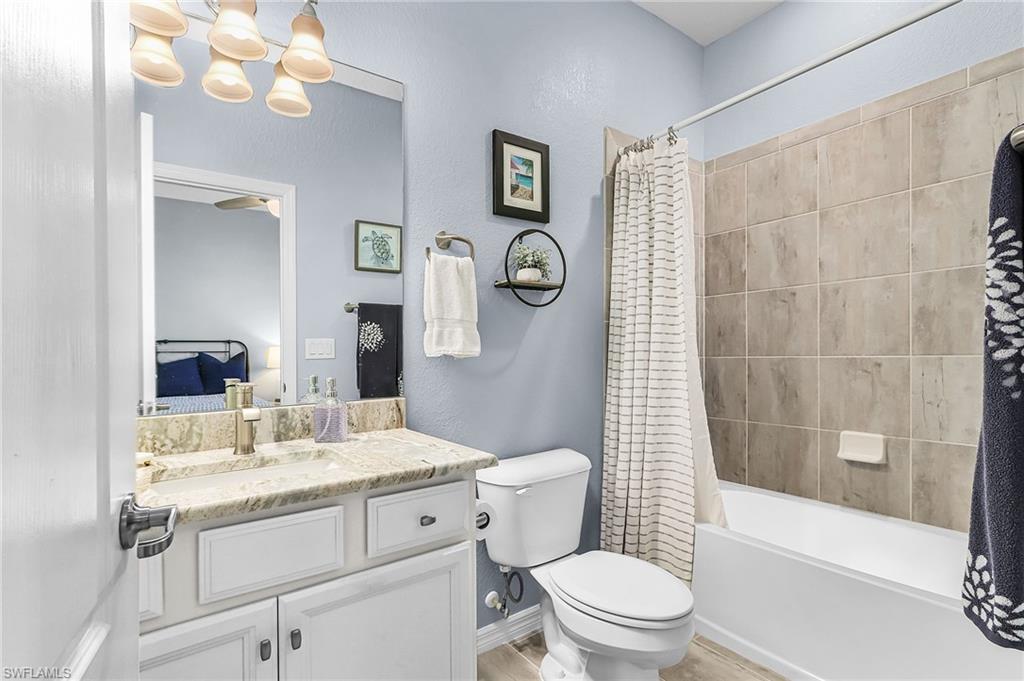 Ensuite bathroom featuring vanity, shower / bath combination with curtain, a chandelier, and a textured wall