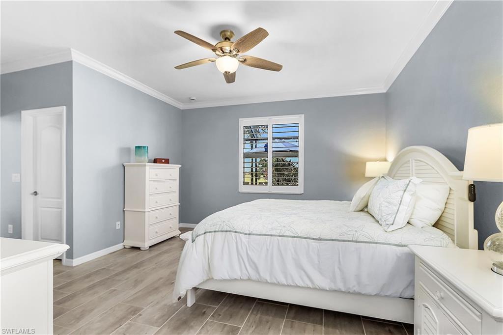Bedroom featuring ornamental molding, wood finish floors, and ceiling fan