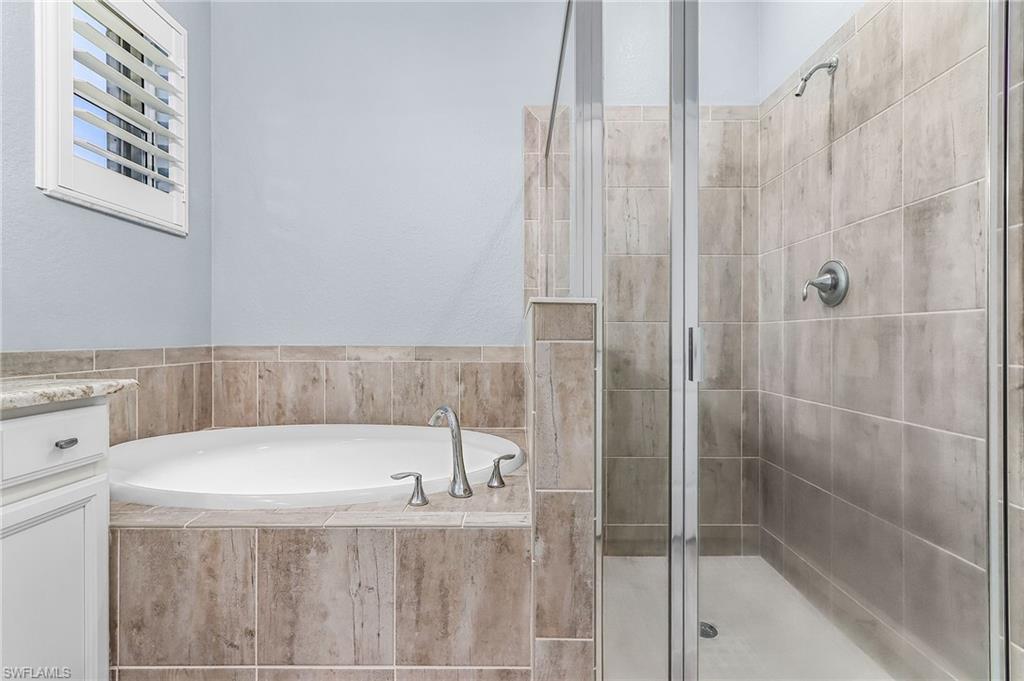 Full bathroom featuring a stall shower, a bath, and vanity