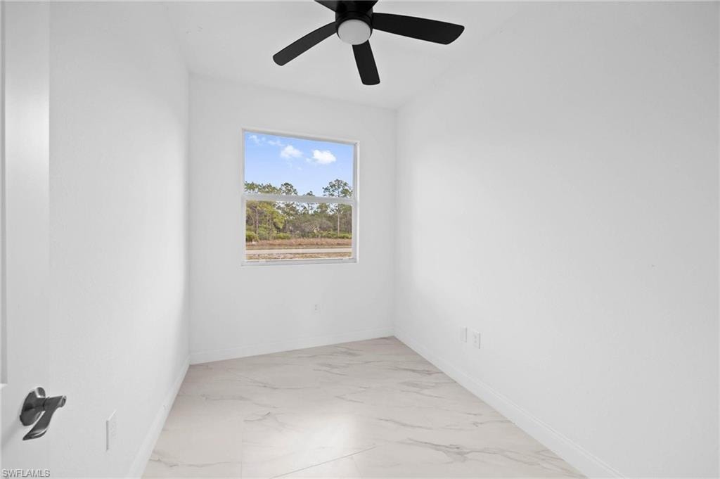 Spare room featuring light marble finish flooring and ceiling fan