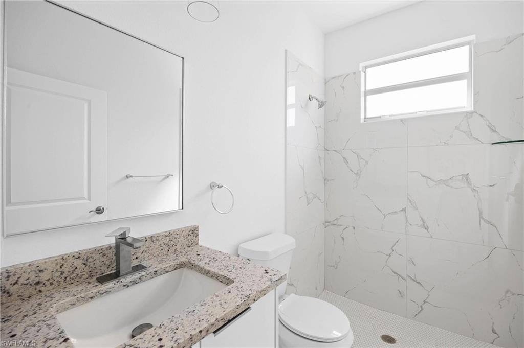 Bathroom featuring vanity and a marble finish shower