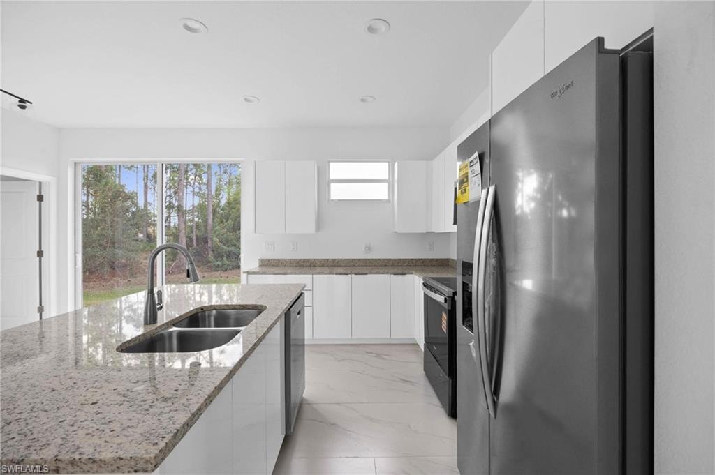 Kitchen featuring stainless steel appliances, white cabinets, modern cabinets, light stone counters, and recessed lighting