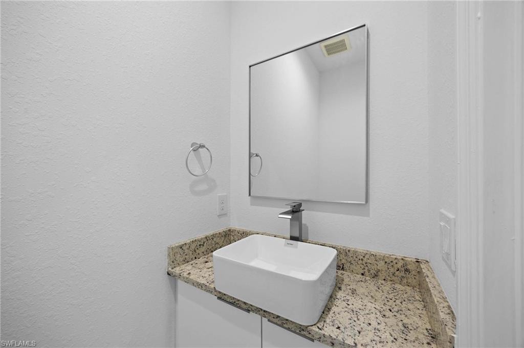 Bathroom with vanity and a textured wall