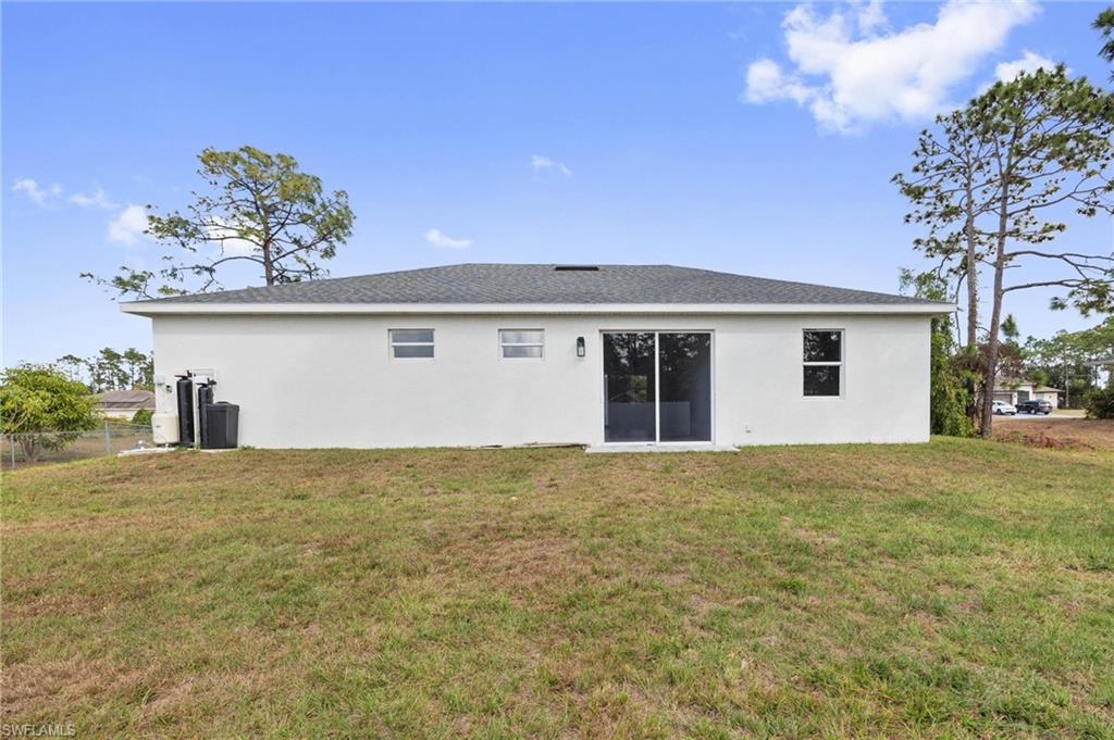Back of property with stucco siding and a shingled roof