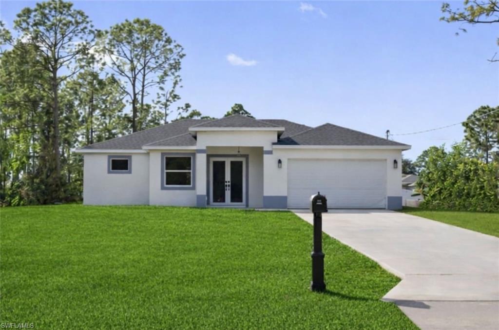 View of front of house featuring french doors, a garage, stucco siding, concrete driveway, and a front yard