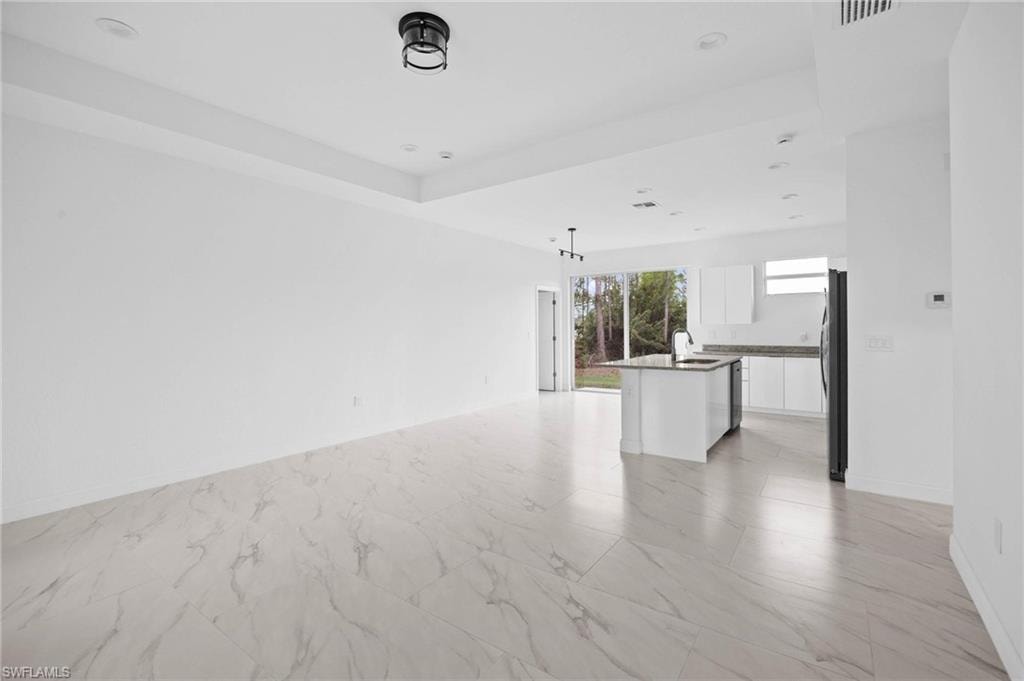 Unfurnished living room featuring light marble finish flooring and recessed lighting