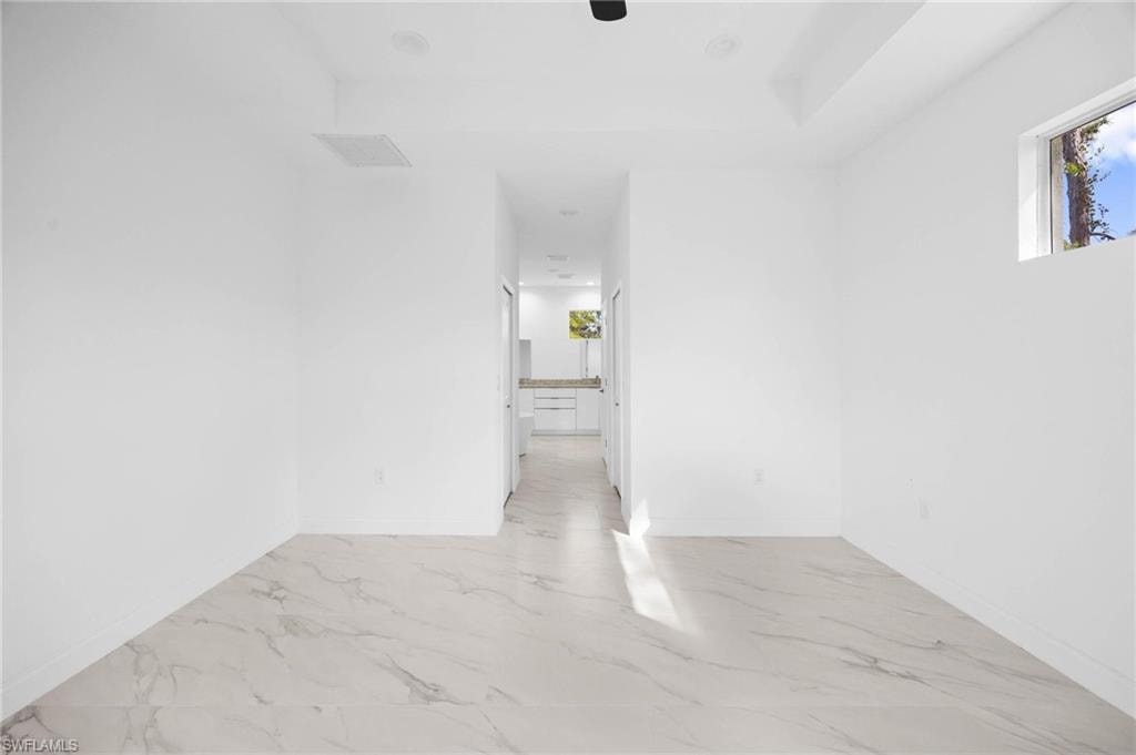 Spare room featuring baseboards and light marble finish floors