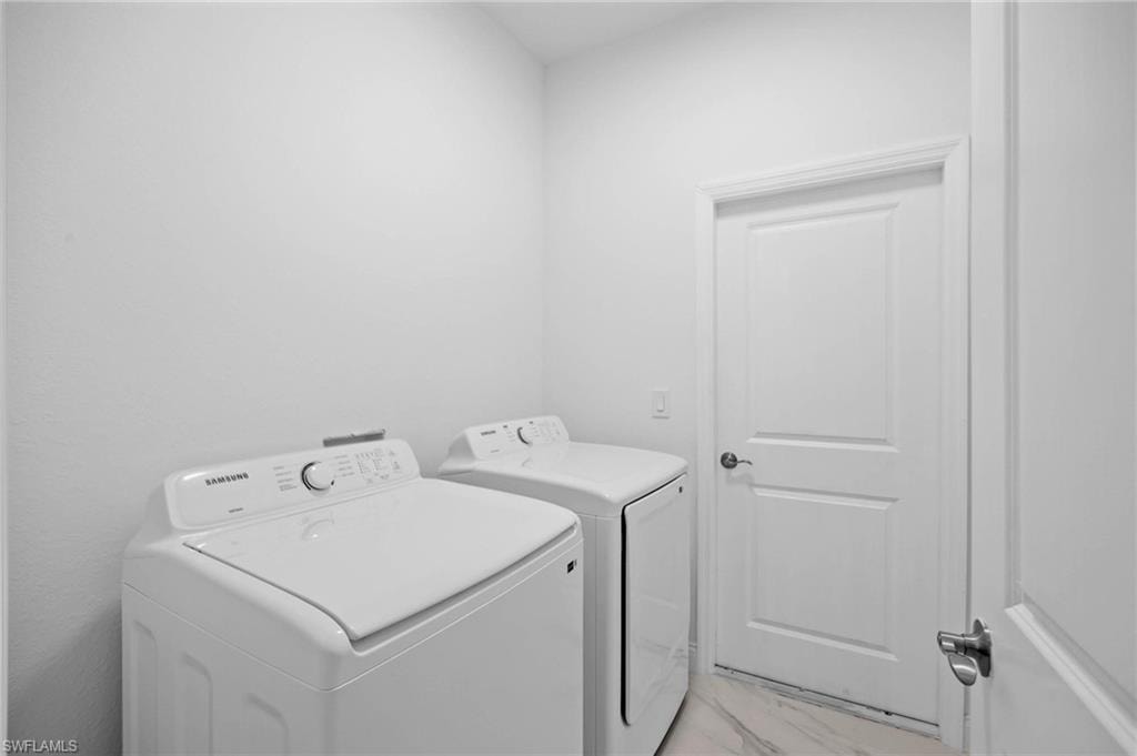 Laundry area featuring washer and dryer and light marble finish flooring