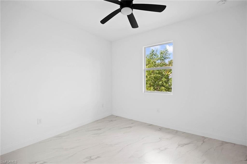 Empty room featuring ceiling fan and light marble finish flooring