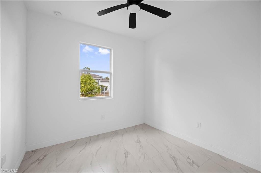 Unfurnished room with light marble finish floors and ceiling fan