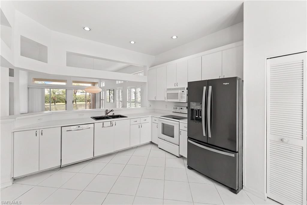 Kitchen featuring white appliances, light countertops, white cabinets, recessed lighting, and light tile patterned floors