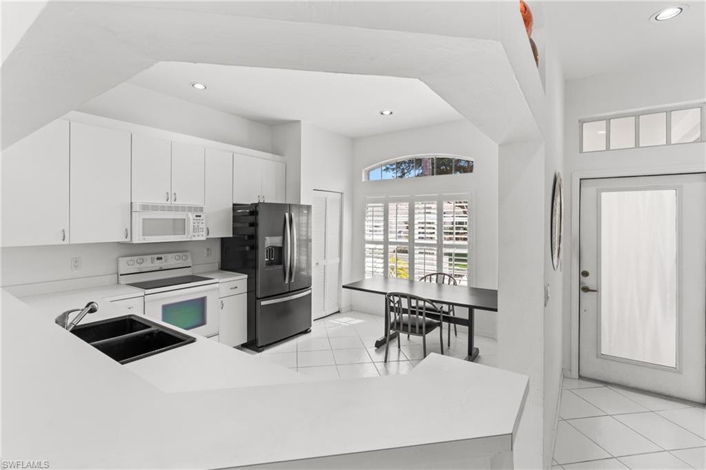 Kitchen featuring white appliances, light countertops, white cabinets, recessed lighting, and light tile patterned floors