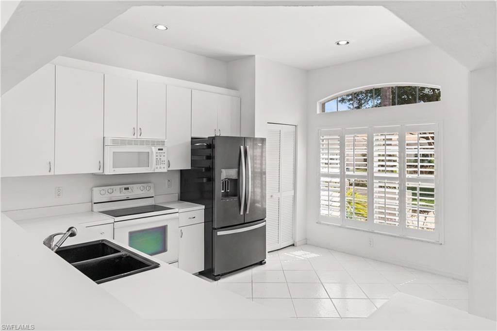 Kitchen with white appliances, white cabinetry, light countertops, light tile patterned floors, and recessed lighting