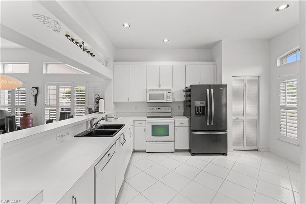 Kitchen with white appliances, light countertops, white cabinets, plenty of natural light, and recessed lighting