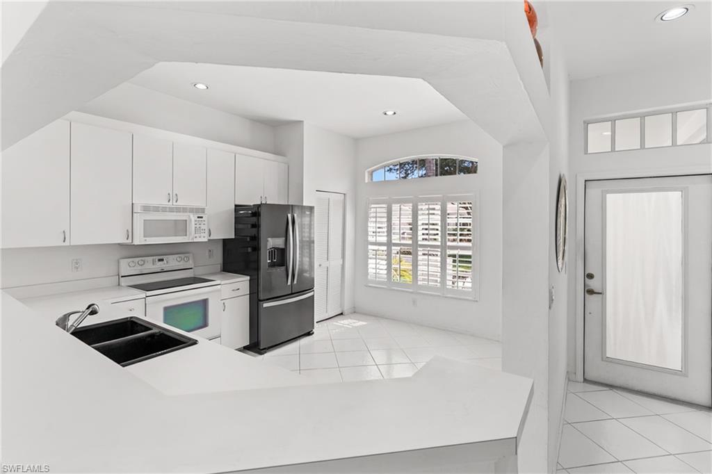 Kitchen with light countertops, white appliances, white cabinetry, light tile patterned floors, and recessed lighting