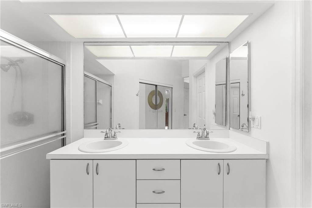 Bathroom featuring double vanity and a shower with door