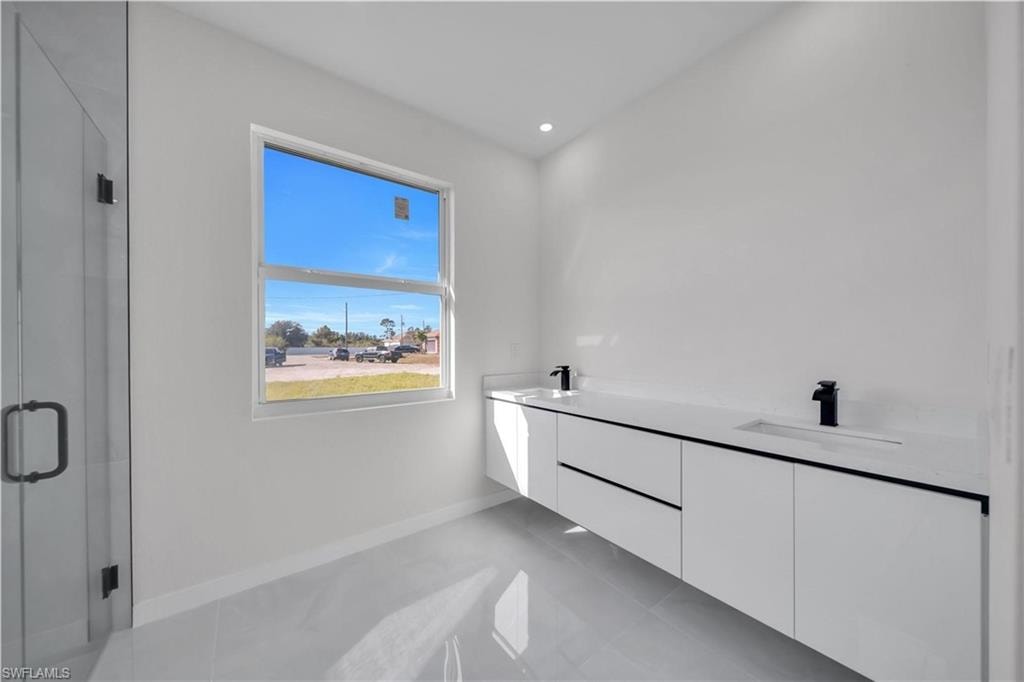 Full bath featuring double vanity, a shower stall, light tile patterned flooring, and recessed lighting