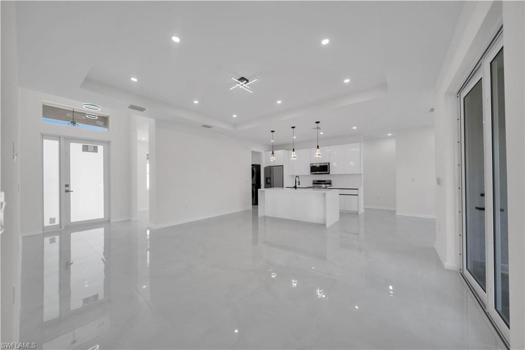 Unfurnished living room featuring a raised ceiling and recessed lighting