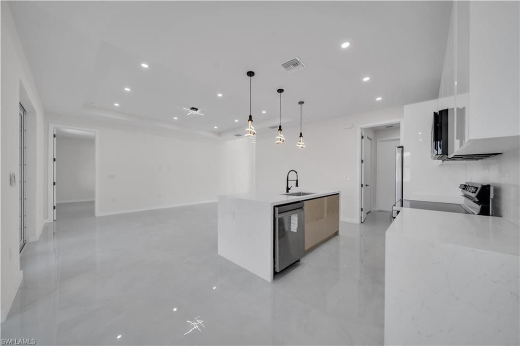Kitchen featuring a kitchen island with sink, light stone counters, open floor plan, and modern cabinets