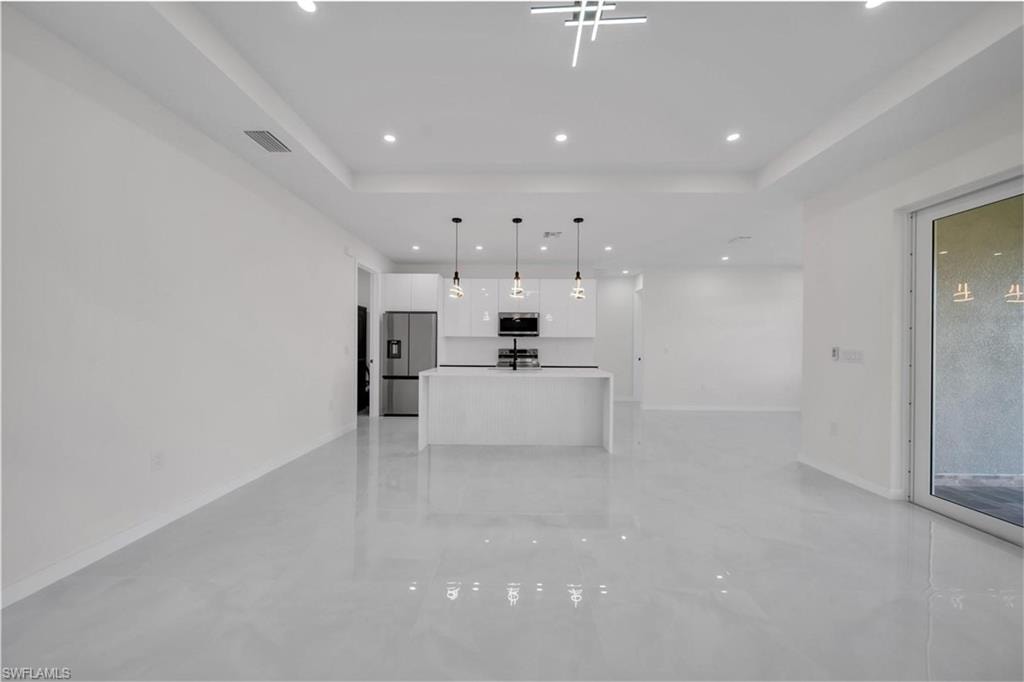 Unfurnished living room with recessed lighting and a tray ceiling