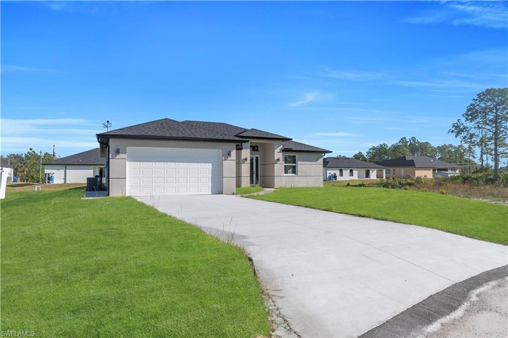 Prairie-style house featuring a front lawn, concrete driveway, stucco siding, and an attached garage