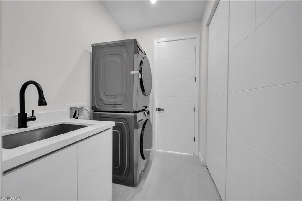 Laundry area featuring stacked washer and dryer and cabinet space