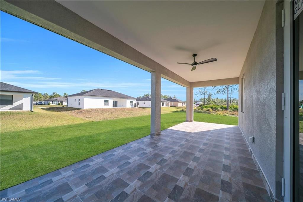 View of patio with a residential view and a ceiling fan